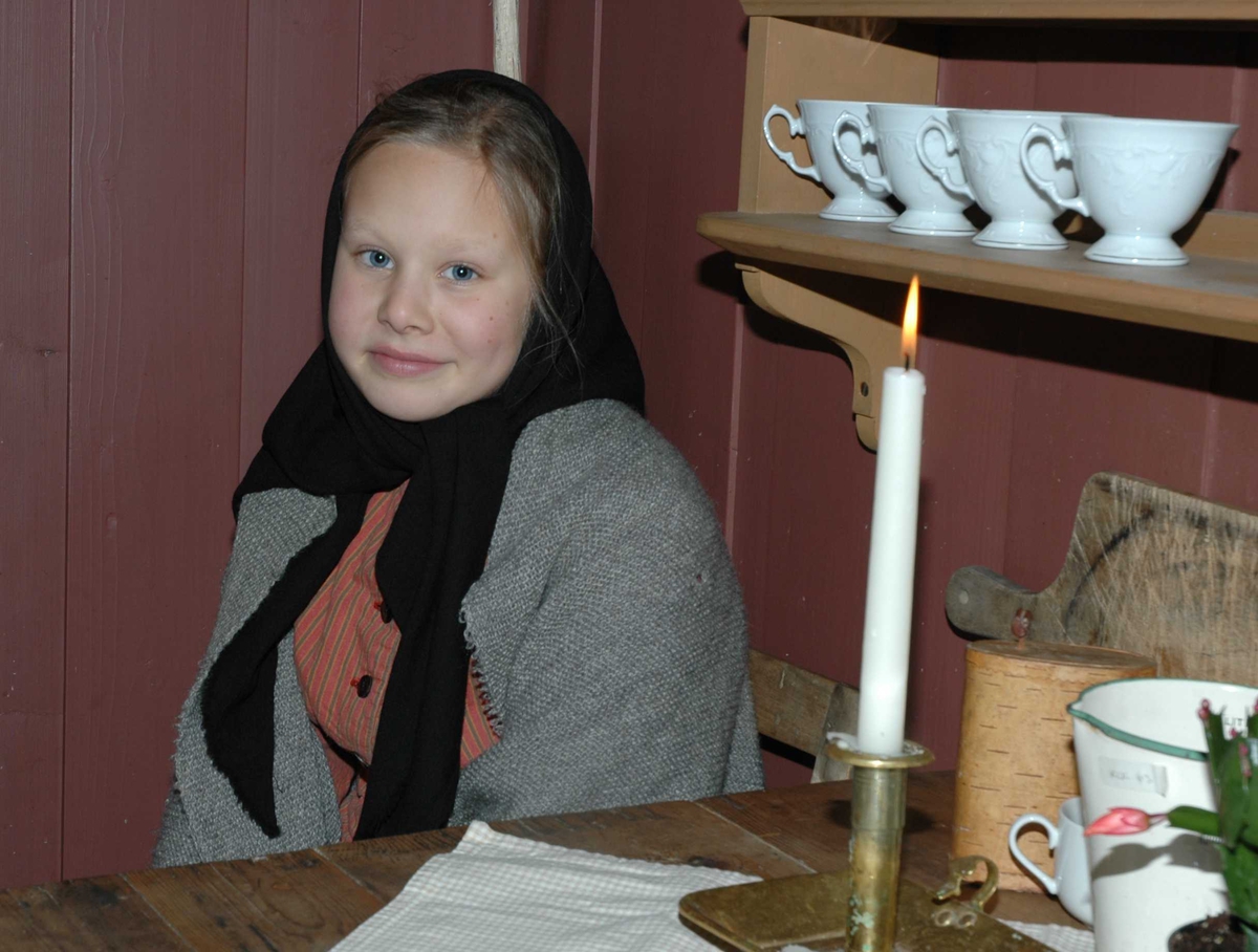 Julemarked 27.11.2005. Jente i tidriktig kostyme ved bordet  i et av husene på Enerhaugen i museets gamleby.