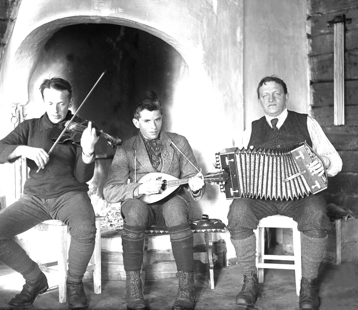 Tre spillemenn, Fritjof Arentz i midten, foran peisen i Fagerstua. Fotografert påsken 1921.