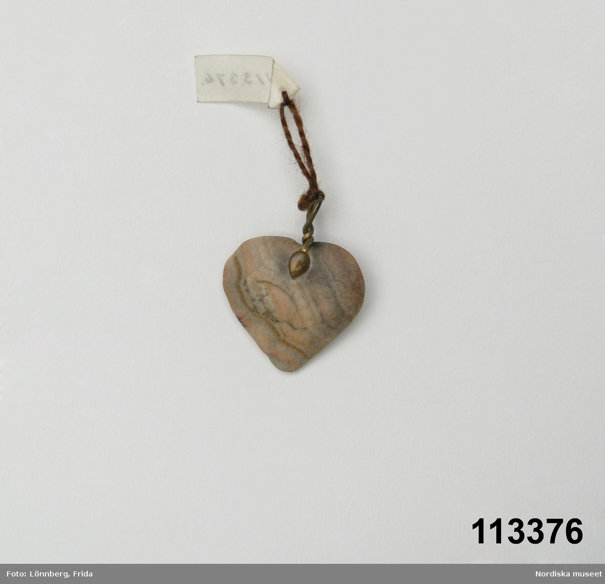 Huvudliggaren:
"Berlock av sten, hjärtformig med hängögla av koppar.
G. 6/4 1909 Elving, Anna Gunborg, fröken, Stockholm."