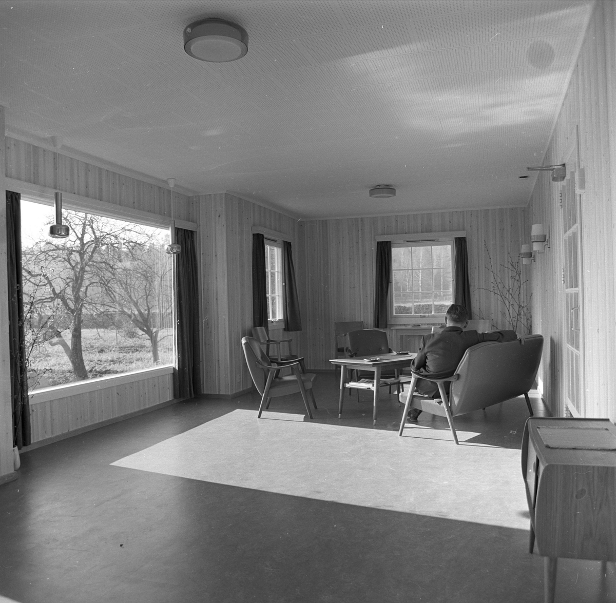  Statens sykehus for epilepsi ,Bærum, 12.03.1964. Interiør med bord og stoler, fra oppholdsrommene, mann sittende i stol.