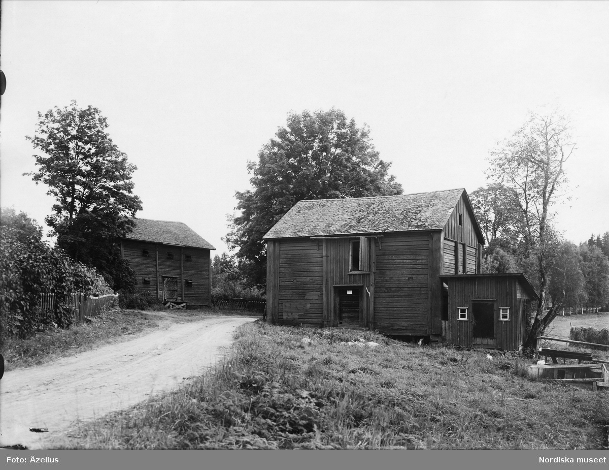 Kyrkoherdebostället, Bodar, Väse socken, Väse härad, Värmland. Uthus av liggande timmer på var sida om en grusväg.
