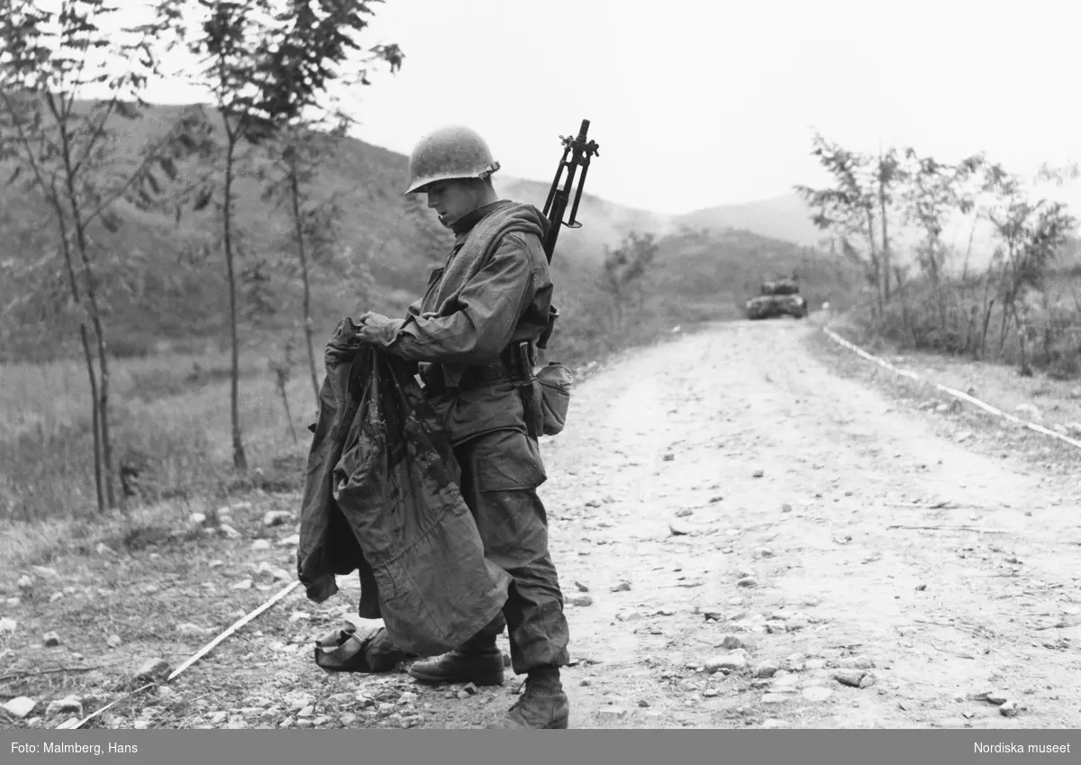 Koreakriget, 1950. Amerikansk soldat håller upp en blodig fältjacka.