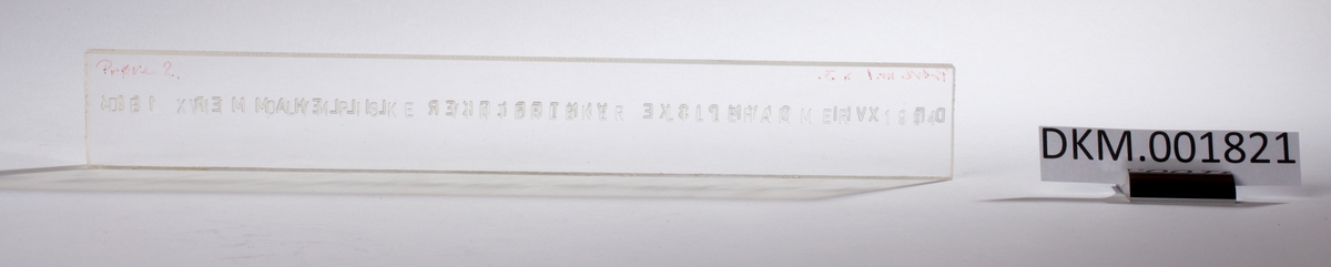 En rektangulær skive med inngravert tekst som er lik på begge sider av skiven.