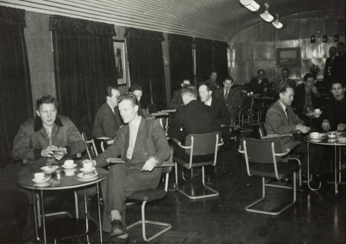 Generalforsamlingen i bedriftsidrettslaget Ø-sport i spisesalen til sykkelfabrikken 14.12.1954: menn sittende ved bordene