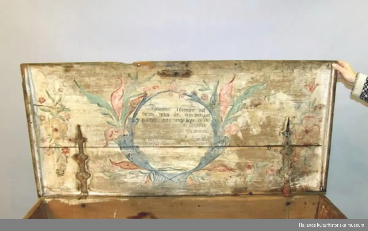 Blåmålad brudkista med två målade blomsterkransar med initialerna LJD samt årtal 1806 på kistans framsida. Sliten målning på locket. På lockets insida vers omgiven av målade blommor.