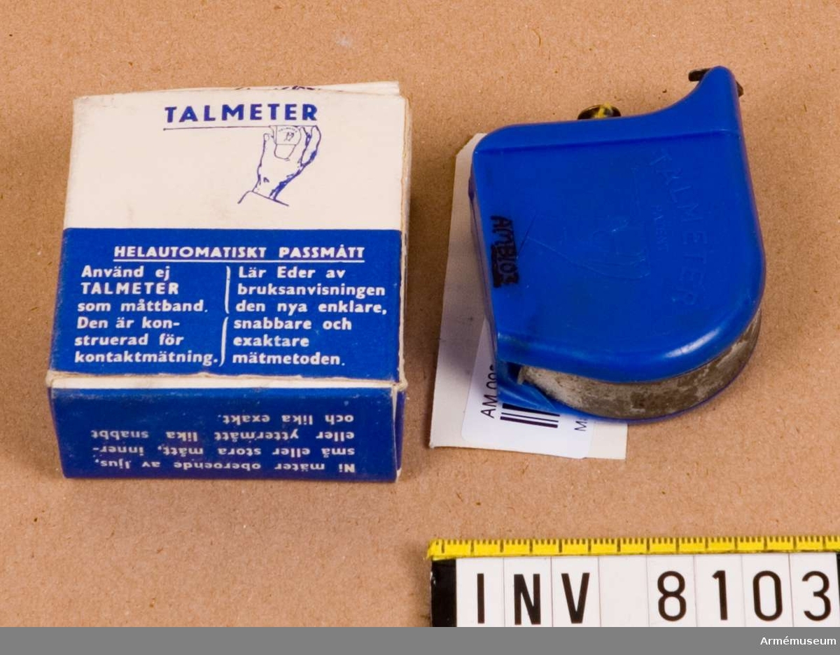 Tillverkad av blå plast och måttbandet av stål. Kåpan är märkt  med "Talmeter patent" och på motstående sida "T. A. LJUNGBERG SWEDEN". Bandets längd är 2 m. Bruksanvisning finns i  förpackningen.Ingår i fotomaterielsats 7 låda 1. 
