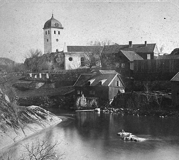 Enligt text på fotot: "Kyrkan och gamla Uddgrenska fastigheten vid Bäveån från sydväst".