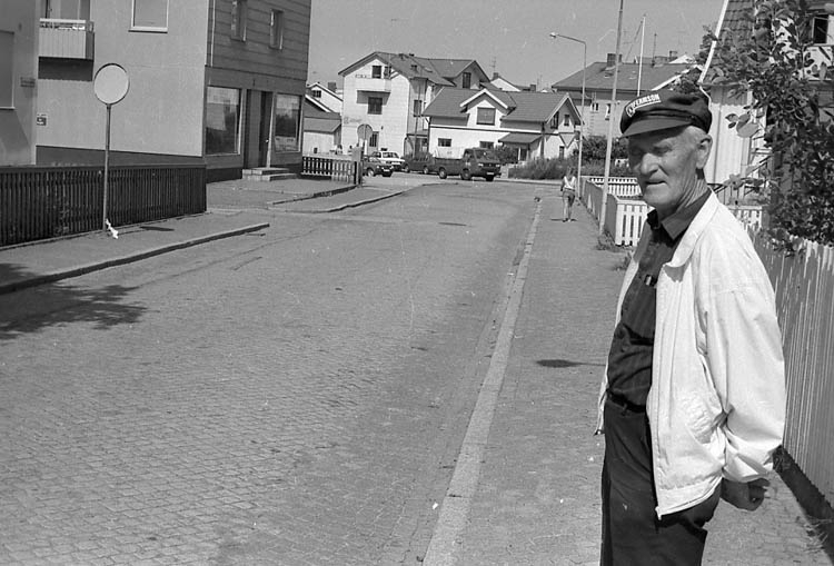 Enligt fotografens notering: "Eric Gunnarsson, Lysekils siste stenhuggare står på stora Kyrkogatan som han själv lagt med smågatsten (knott). Nu skall gatan istället få asfalt".