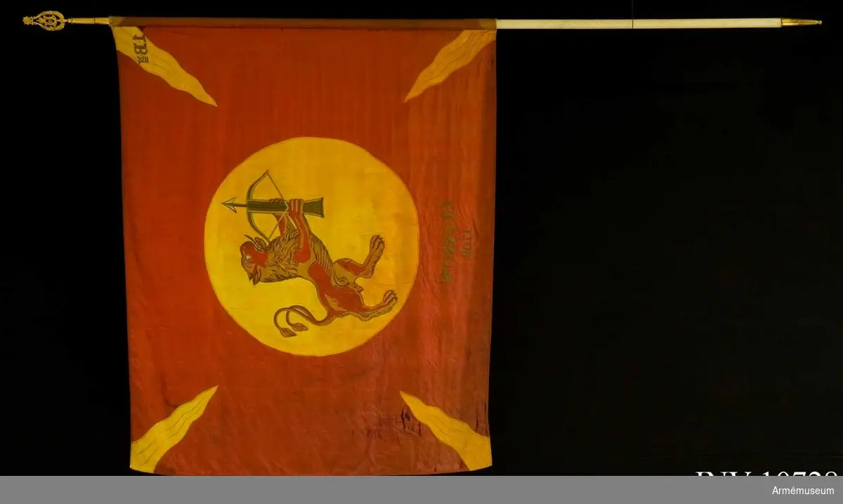 Grupp B.

Duk av rött, fyrskaftat fansiden (kypert), med från hörn och sidornas mitt ingående 4 st flammor av gult liknande siden. I mitten, broderat lika påbåda sidor, Smålands vapen, i gult fält (830 mm) ett rött lejon förande ett spänt armborst med pålagd  pil. Lejonet av rött fansiden med man och skuggning i bruna  och violetta silken, tänder och klor i silver. Armborstens  stock brunt siden, silvertyg i bågen och och pilen, kantsömmar i plattsöm i olika silken. Segernamn under vapnet, genombroderat i guld: Clissow 1702. Kantad med sidenband och fäst med förgyllda spikar. Kravatt: blå och gul av fansiden, med pil och frans. Längd 1920 mm, bredd 290 mm. Stången av furu, målad vit. Doppsko av förgylld mässing. Spetsen av förgylld mässing. Ett fodral tillhör också. Fodralet i svart kläde med skinnskodd spets, dragsko och ficka för spetsens blad. Längd 1840 mm, bredd 180  mm.