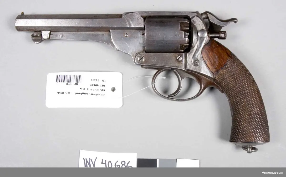 Grupp E III. 
Revolver för tändhattar. London 1850-1860. Loppets rel. längd: 12 mm.Keres system. På det högra kolvbeslaget står: London Armoury. Tillverkningsnummer 3463. På pipans vänstra sida bokstäverna: L.A.C.