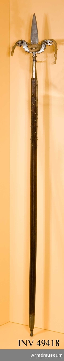 Grupp D I. 

Apterad som luntstake (porte mèche de canonia).
Ett antal av de dekorationsstift av mässing som pryder skaftets övre del saknas, (111 av 198 st). 