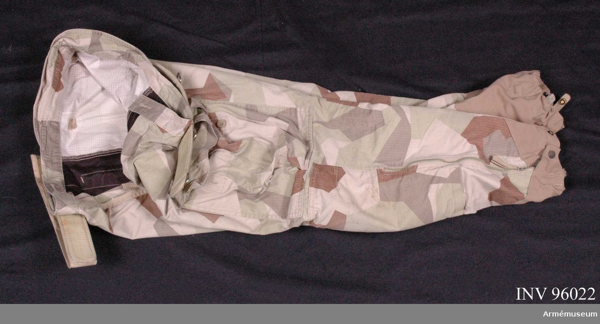 Utförda i ökenkamouflage.
Tillverkade 2009 i Kina.
På byxorna sitter en livrem (AM.096023).
Med tillhörande knäskydd.