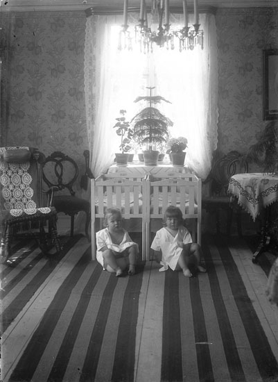 Tvillingarna Karl Erik och Gustav sitter på varsin potta nedanför sängarna i ett rum inrett i oscariansk stil, Holstska huset på Nösund