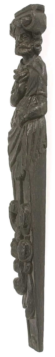 Hermpilaster.
Liten skulpterad pilaster föreställande skäggig herm under joniskt kapitäl.
Huvudet är vridet mot vänster. Hermen är insvept i en mantel som hålls fast med vänster hand framför magen. I höger hand håller figuren ett okänt föremål (blomsterkälk?) framför bröstet. Pilasterskaftet är prytt med stora frukter och blad, fasthängande vid en stängel som delvis täcker det nedåt avsmalnande skaftets ramverk. Baksidan är slät.
Skulpturen är mycket välbevarad med sju spikhål.

Text in English: Small sculpted pilaster with a bearded Herm beneath an Ionic capital.
The head of the figure is turned to the left. The Herm is enveloped in a mantle, held fast with the left hand in front of its stomach. Its right hand holds an unknown object (a bunch of flowers?) in front of its breast. The shaft of the pilaster is decked with large fruit and leaves hanging from a stalk which partly cover the framing of the tapering shaft. Its back is flat.
The sculpture is very well preserved.