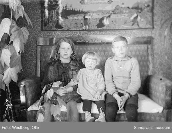 Grupporträtt, tre barn i en soffa.