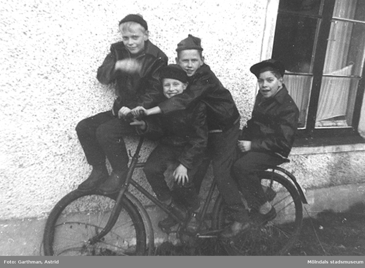 Fyra killkompisar som poserar på en cykel vid Barnhemsgatan 21 ungefär 1957-1958. Från vänster: Roger Karlsson, Alf Garthman, Sune Johansson och Lennart Hedberg.