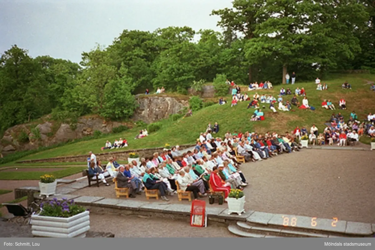 Människor som sitter och tittar på ett musik- och teateruppträdande på Gunnebo slotts framsida.