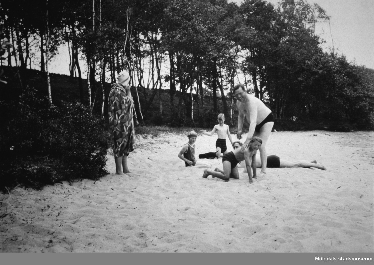 Två män, en kvinna och tre barn på en sandstrand, troligtvis vid Tulebosjön, 1930-tal.