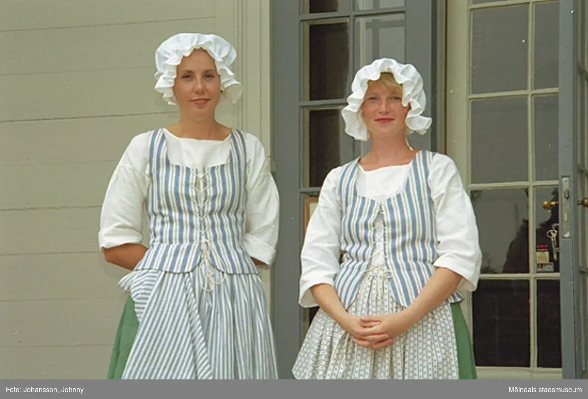 Lotta och Eva står på slottstrappan i tidstypiska kläder (tjänstefolkskläder från 1700-talets slut).