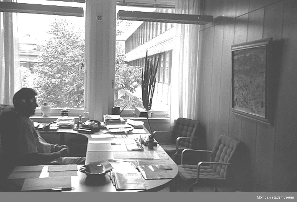 En okänd man sitter vid ett skrivbord i ett kontorrum. Mölndals stadshus, juni 1994.