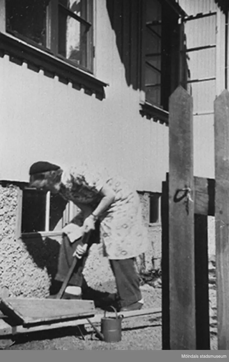 En lärare planterar blommor utefter
 väggen vid 
Krokslätts daghem, Dalhemsgatan 7 i Krokslätt år 1949.