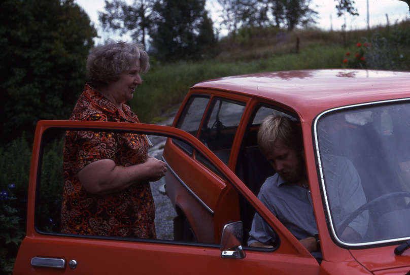 Lantbrevbäraren Mikael Mattsson besöker Maj-Britt Wessberg i Räfsta i Vallentuna. Han sitter i bilen, hon står vid den öppna bildörren.