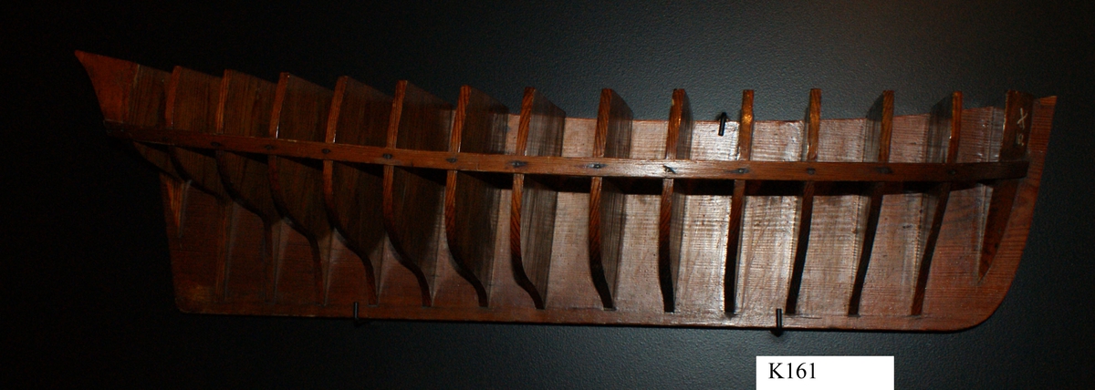 Gavelmodell å fartyg byggt på örlogsvarvet i Karlskrona. Halvmodell av ett mindre segelfartyg troligen från 1700-talet, med akterspegel, utan galjon och utmärkning av däck, men med uppbyggd stäv och köl. Modellens för- och akter utförda av massivt trä och däremellan är fastsatt 13 träskivor, gavlar, som utmärker skrovformen. Gavlarna är fixerade av en ribba. För, akter och gavlar fastsatta på en träplatta. Allt fernissat.