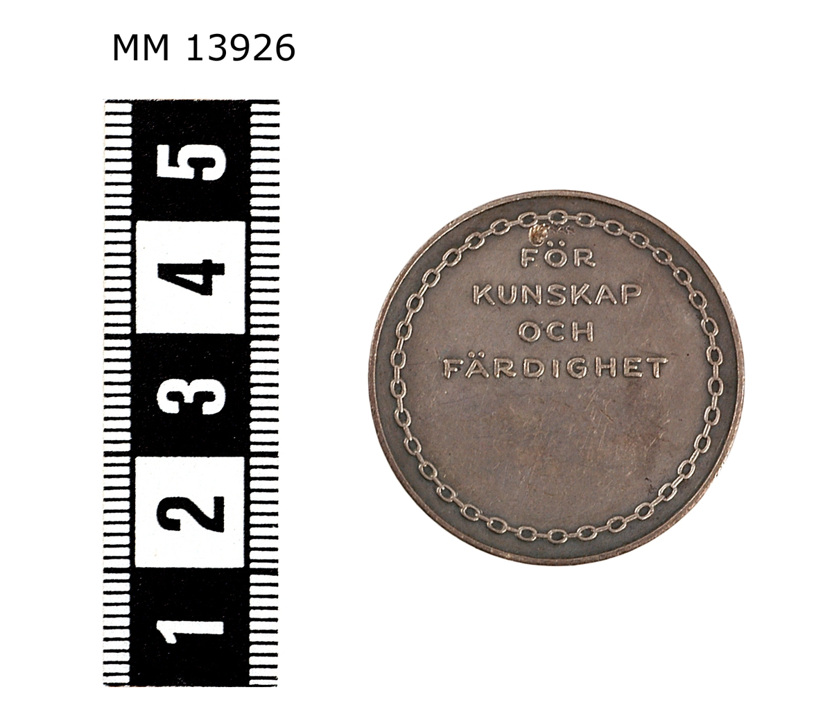 Medalj i silver. På framsidan ett ankare samt texten: Skeppsgossekåren. På baksidan, texten: för kunskap och färdighet. Märkning i kanten: Silver 1932.