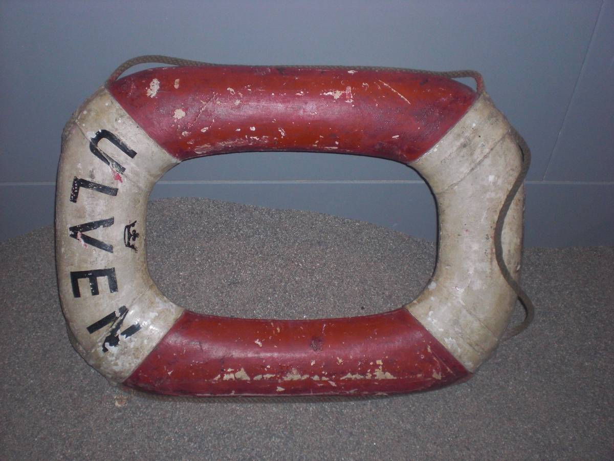 Oval livboj av kork insydd i väv, röd- och vitmålad. Har tillhört ubåten ULVEN.Föremålets form: oval