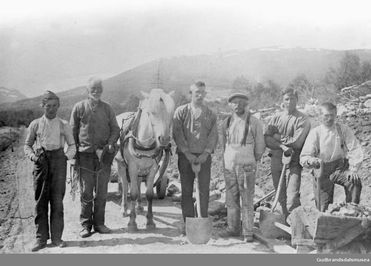 Seks menn driver veiarbeid, kjøring av stein med hest og kjerre.