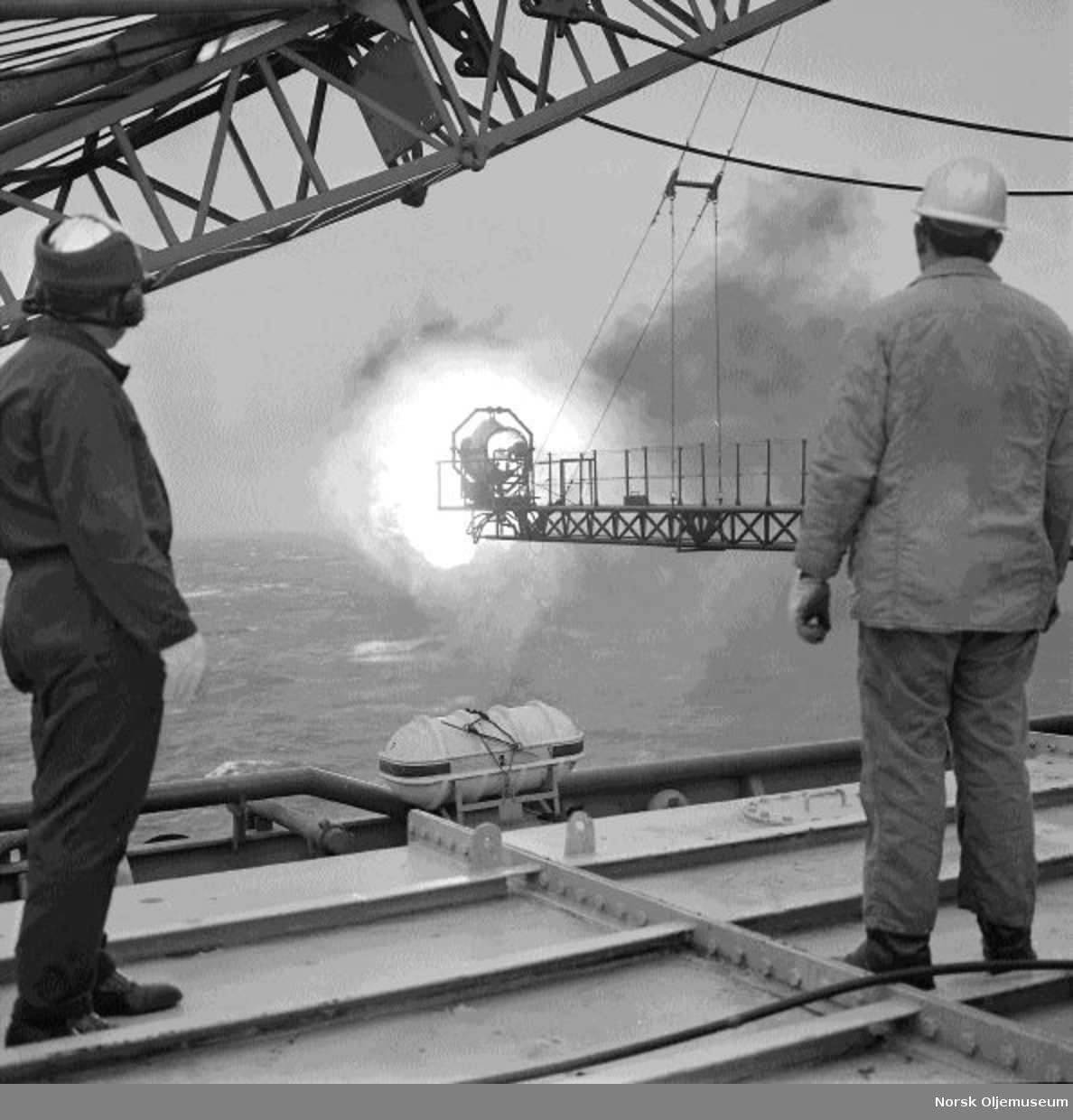 To menn studerer en flammebom på boreplattformen "Gulftide".
