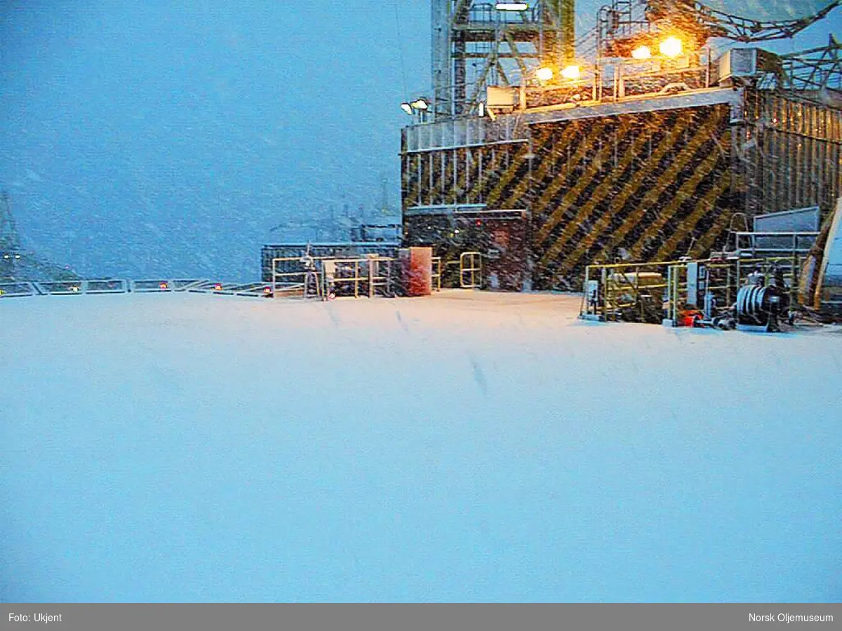 Vinter på Friggfeltet.  Snøfall på helikopterdekket til QP-plattformen.  Helikopterhangaren til høyre i bildet.