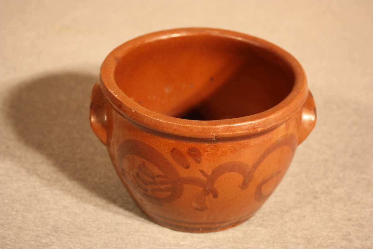 Rund, brun og lett maga keramikkrukke med to øyre og strekdekor i mørkare brunt
