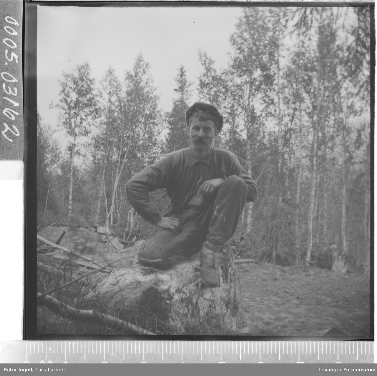 Portrett av en mann som sitter på en trerot.
