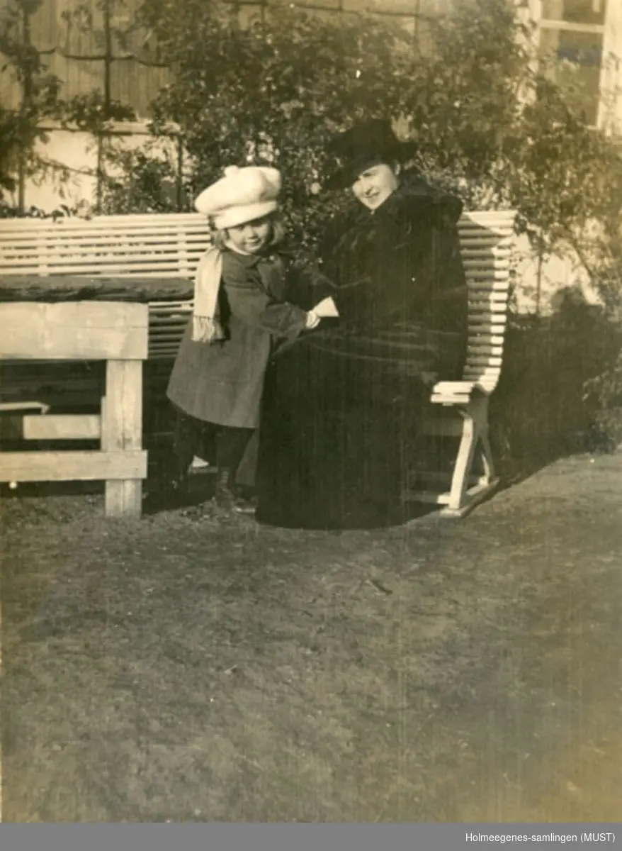 En kvinne og en liten jente på en hagebenk utenfor Holmeegenes i Stavanger. Begge er vinterkledte.