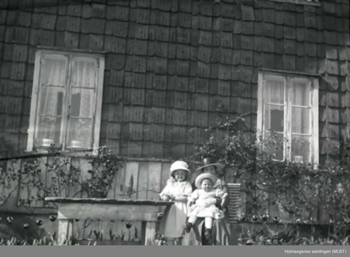 En kvinne og to små jenter foran huset på Holmeegenes i Stavanger.