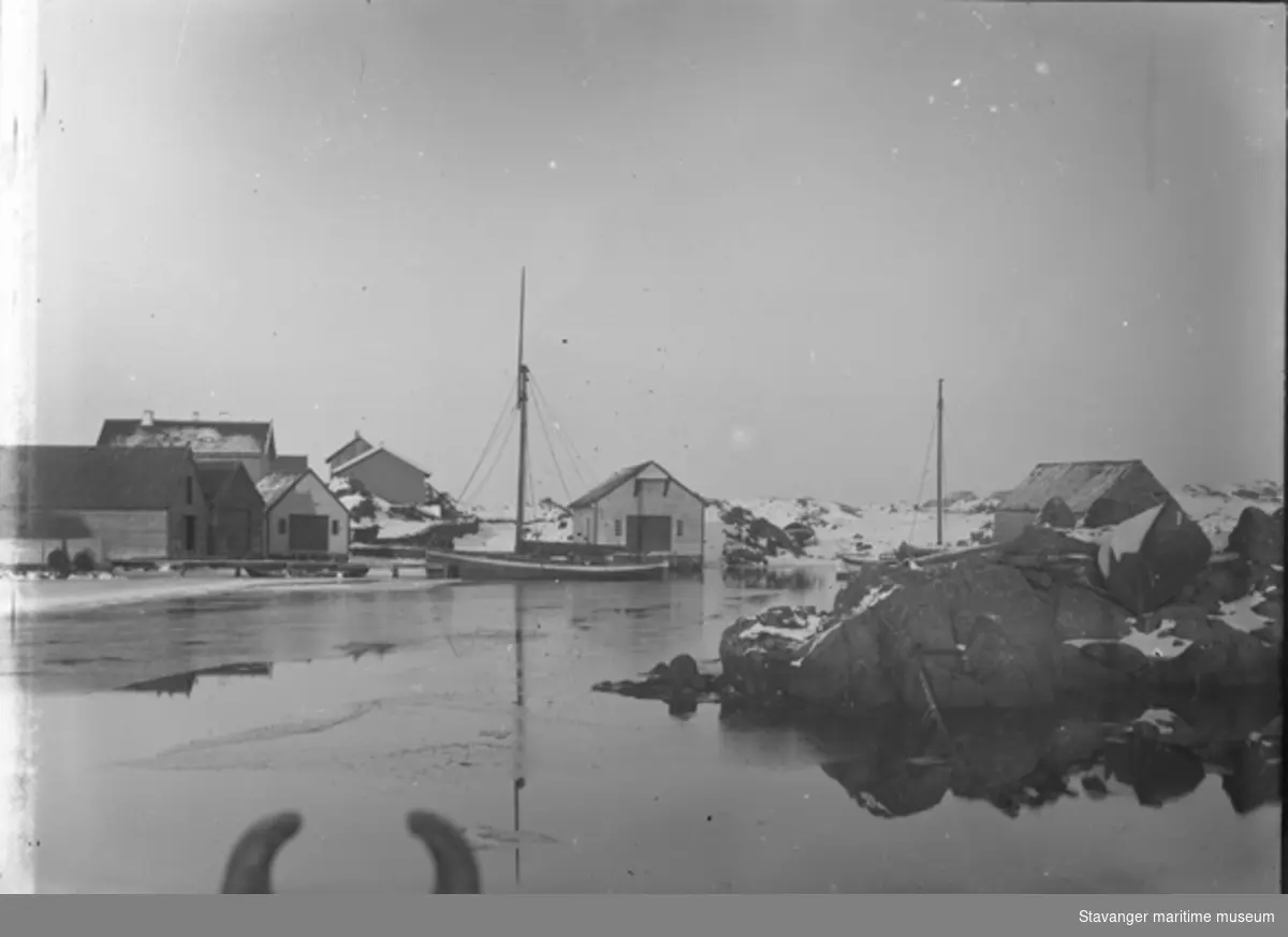 Klynge med sjøhus på Kvitsøy. Havnen er islagt.