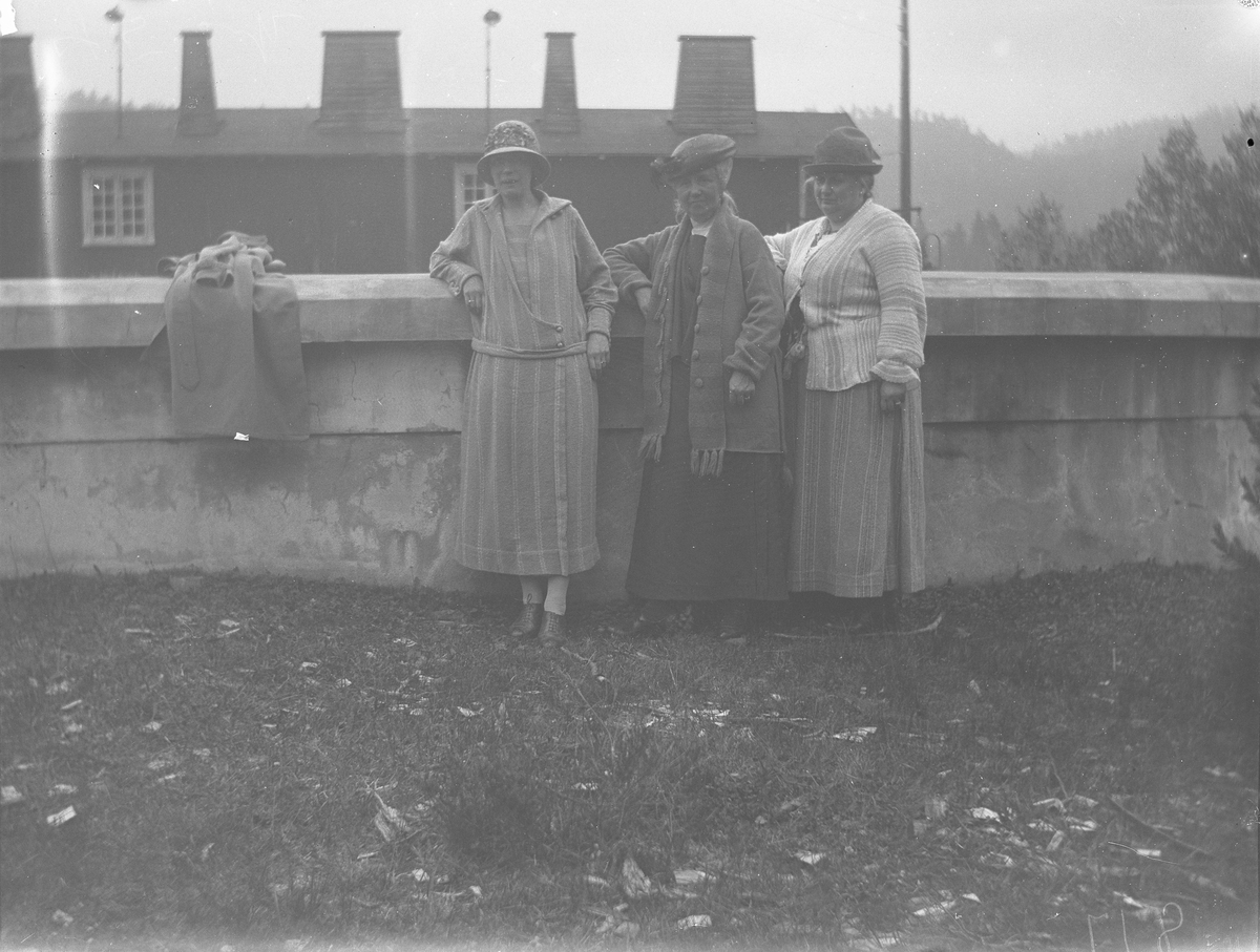 Tre kvinner ved mur foran hus (neppe i Kragerø)