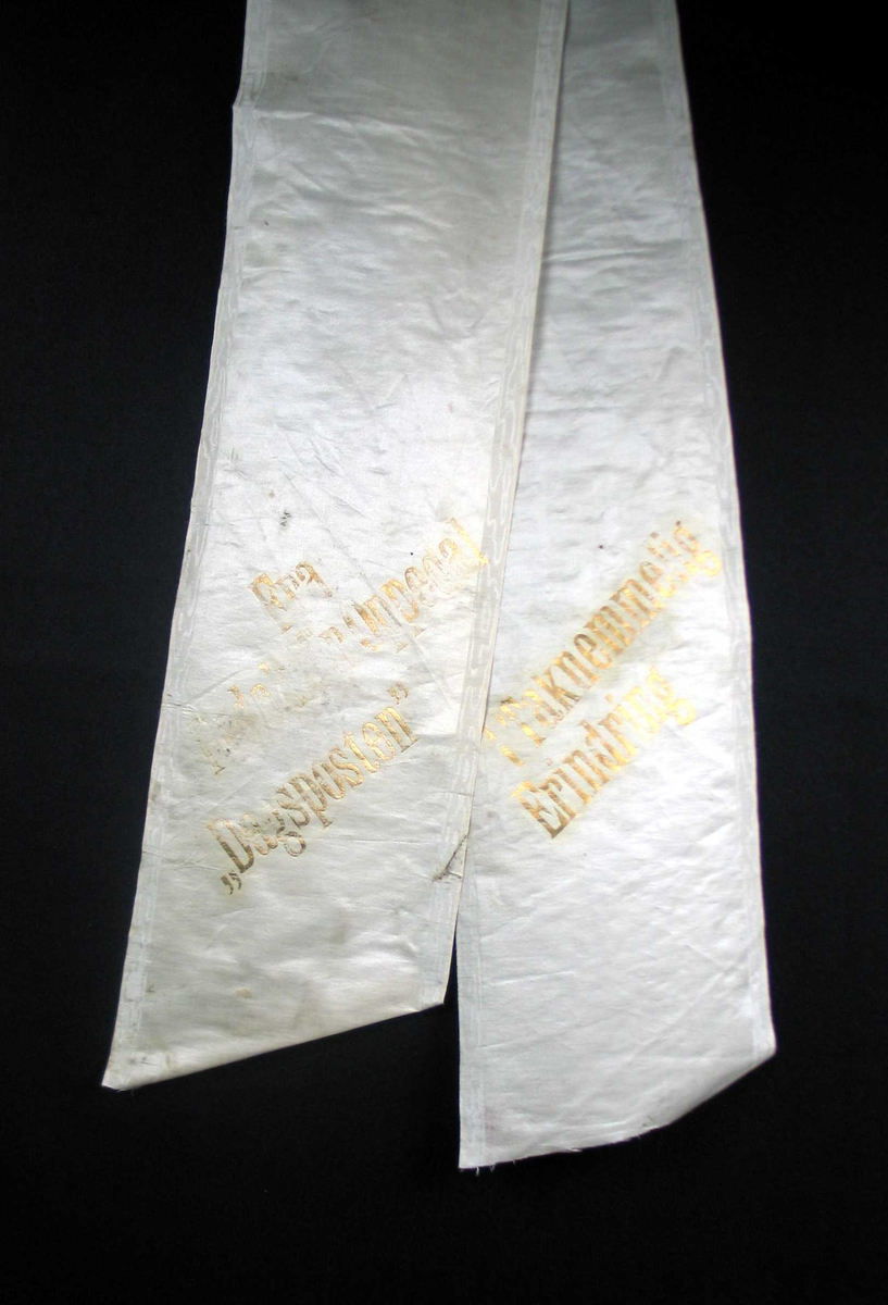 Begravelsessløyfe i hvit silke med tekst i gull.