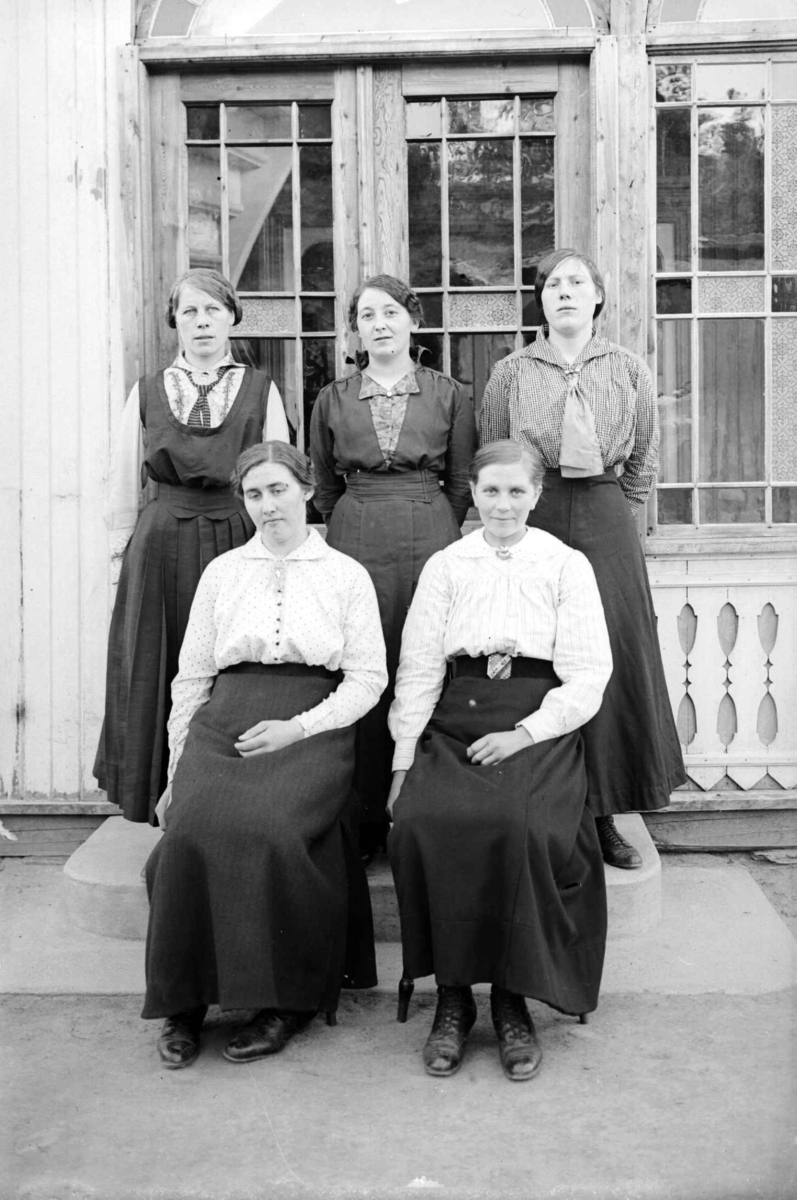 Fem kvinner, tre stående og to sittende 