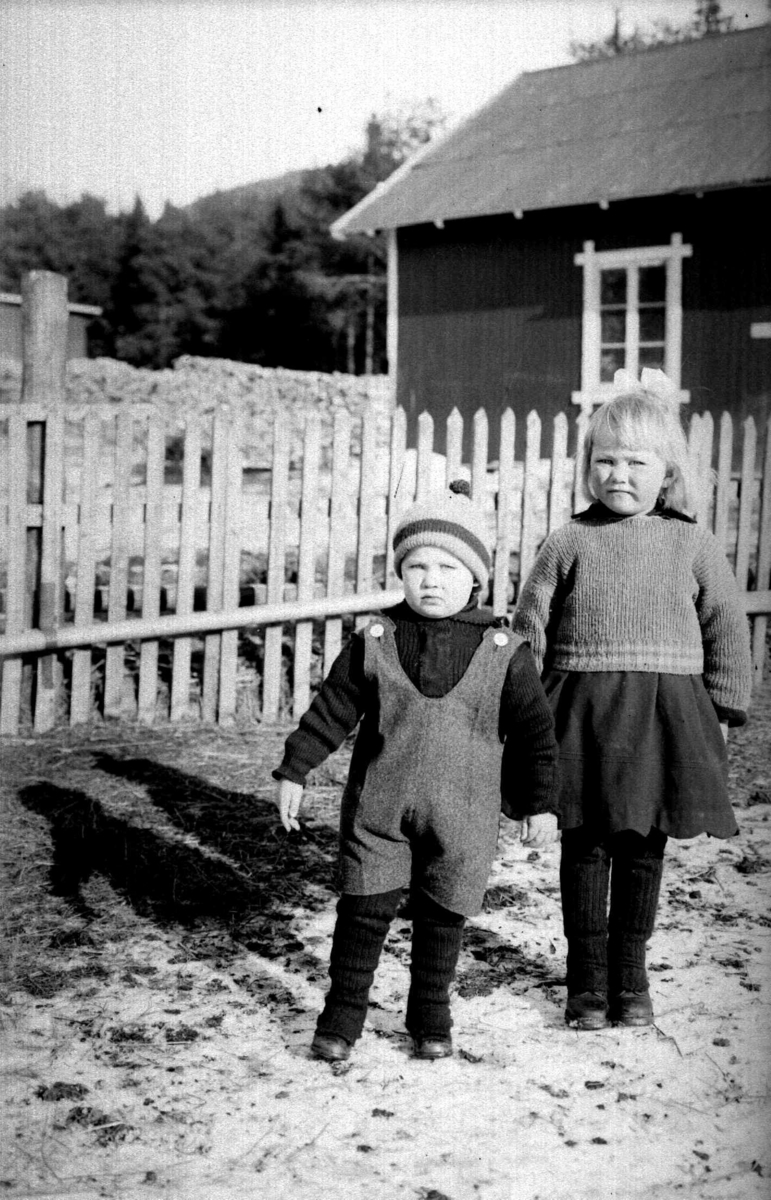 En liten pike og gutt foran et hus