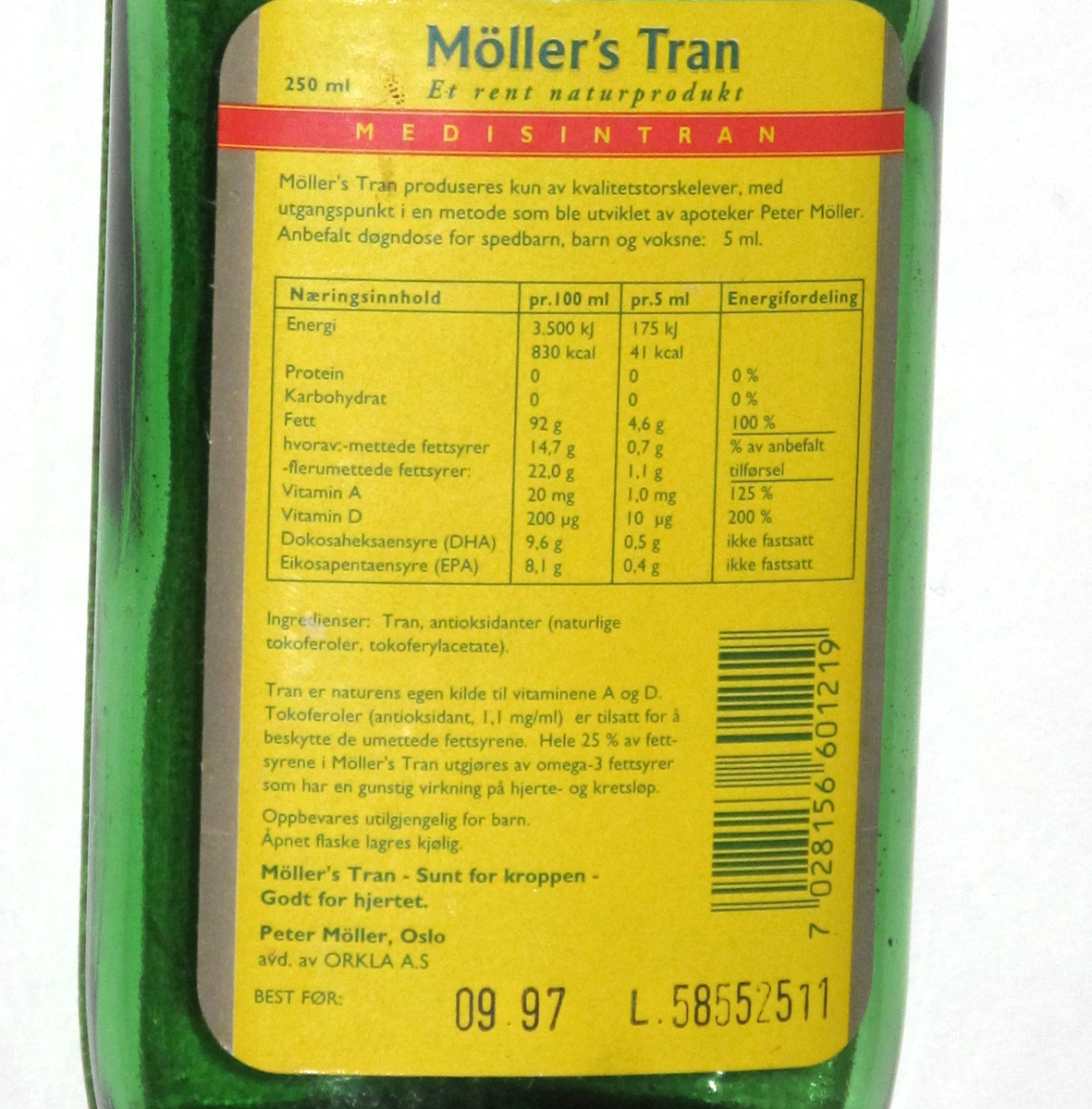 Flaske av grønnfarget glass, med gul etikett, til  tran. 250 ml.  Etikett med opplysninger om  innhold og oppbevaring, varemerke, utmerkelser og strekkode.
