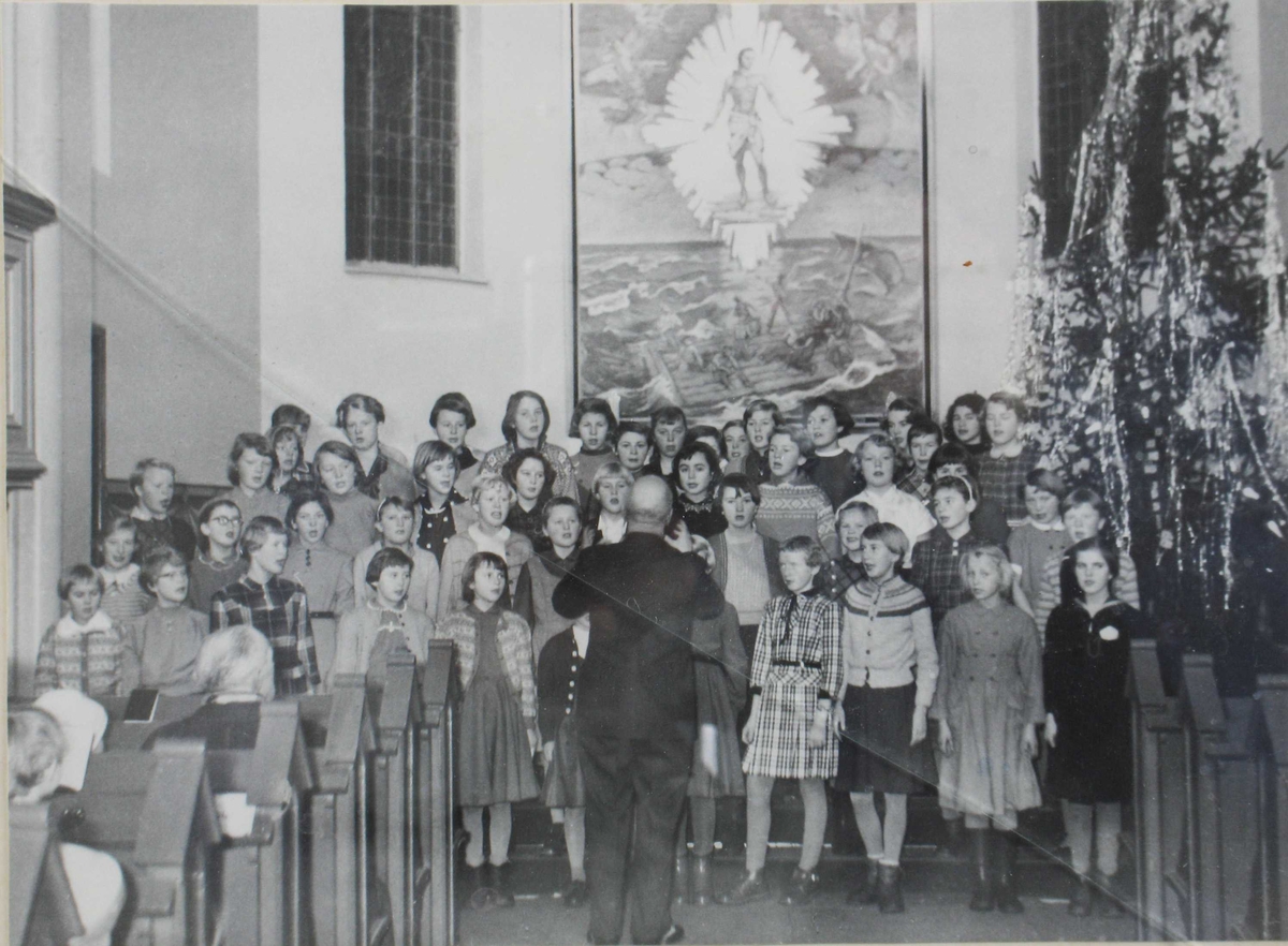 Elever fra 5, 6 og 7 klasse ved  Barbu skole synger i Barbu kirke på julaften 1956. Alterbilde i bakgrunnen, stort juletre til høyre. 