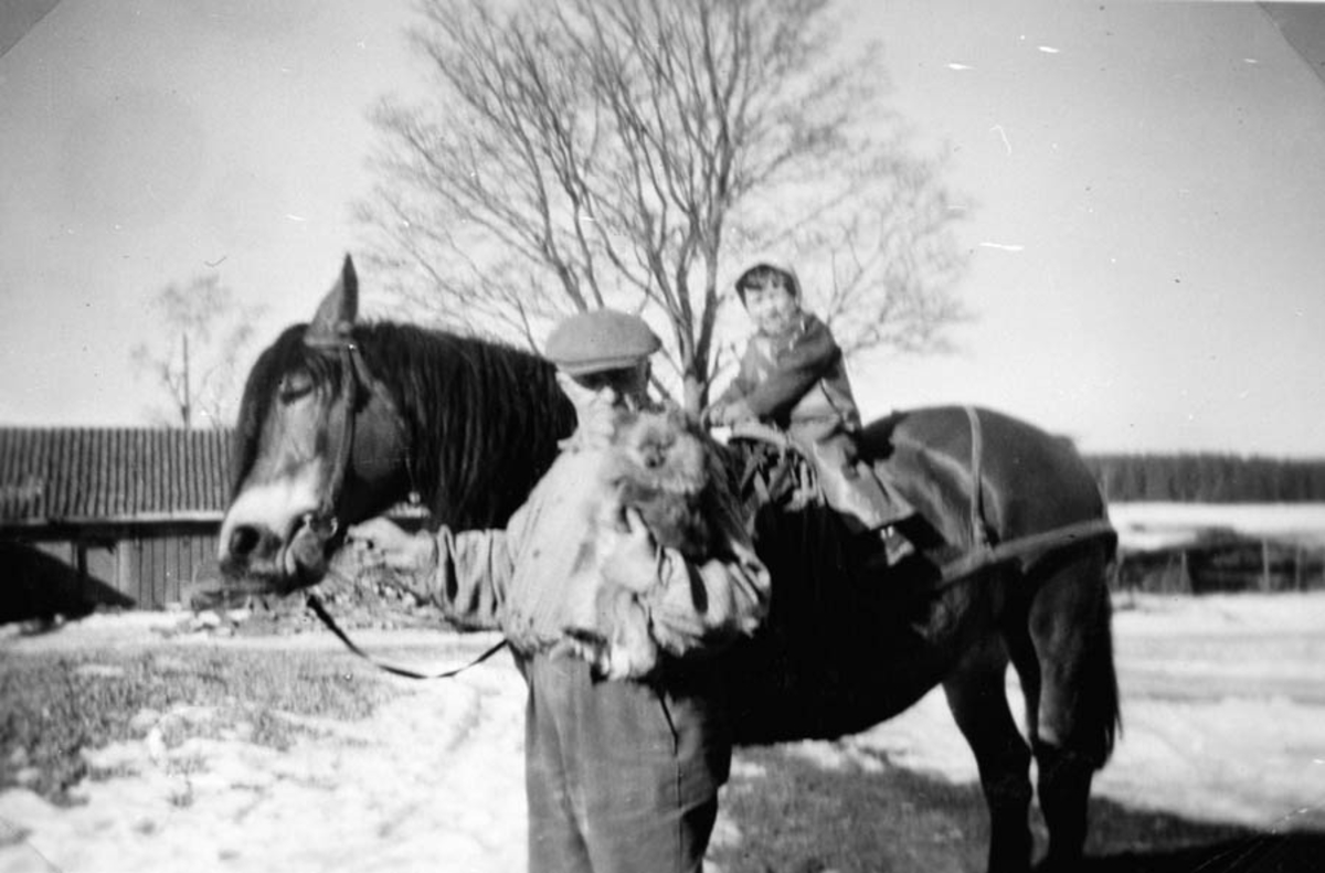 Mann med hest som har et barn på ryggen.