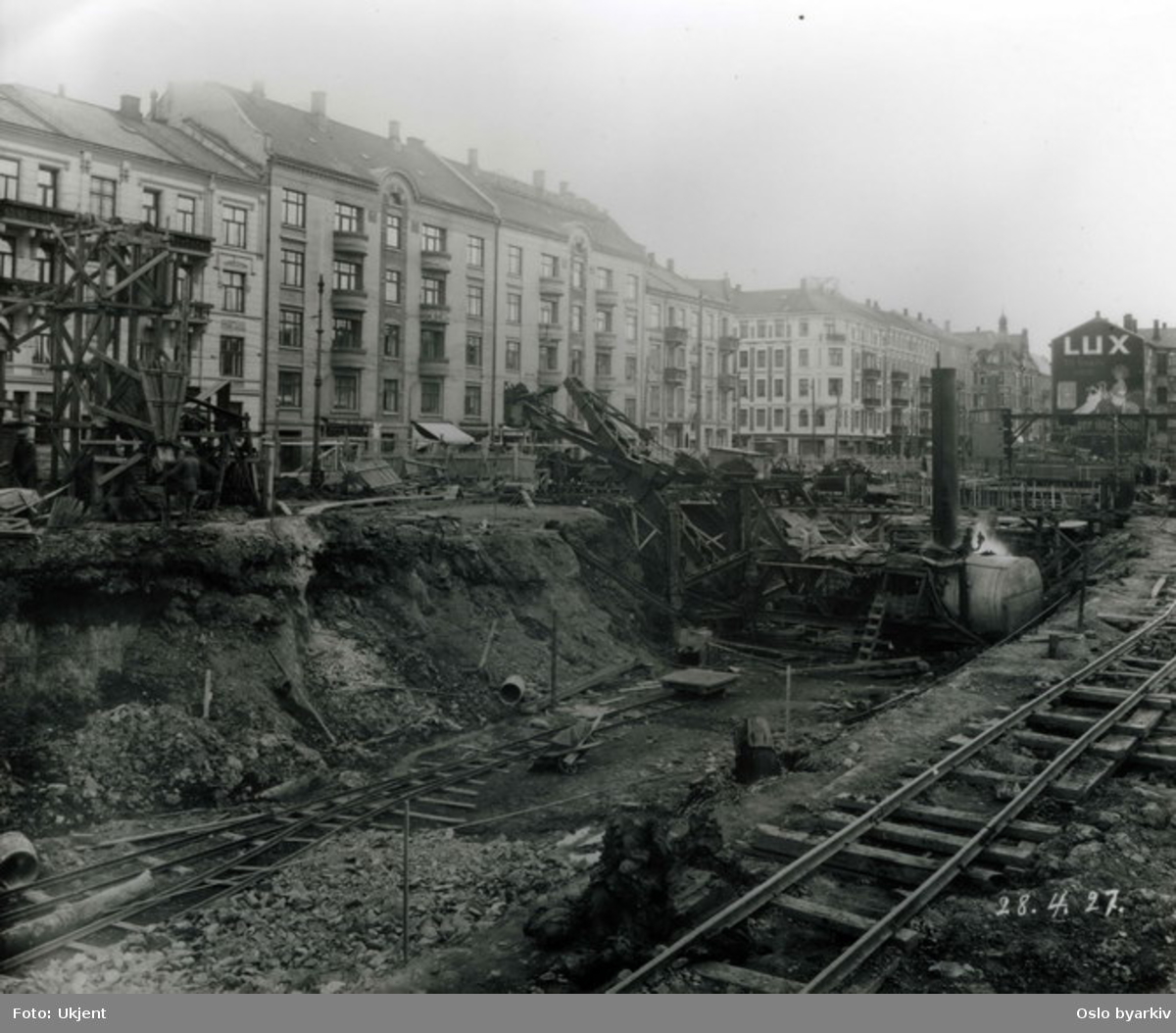 Anleggsarbeide på Majorstuen ved utgravning av tunnel mellom Majorstuen og Nationaltheateret for Holmenkollbanen. Valkyriegata til venstre i bildet. Reklame for Lux sepe på tverrvegg. Fotografiet er merket med datoen 28.4. 1927.