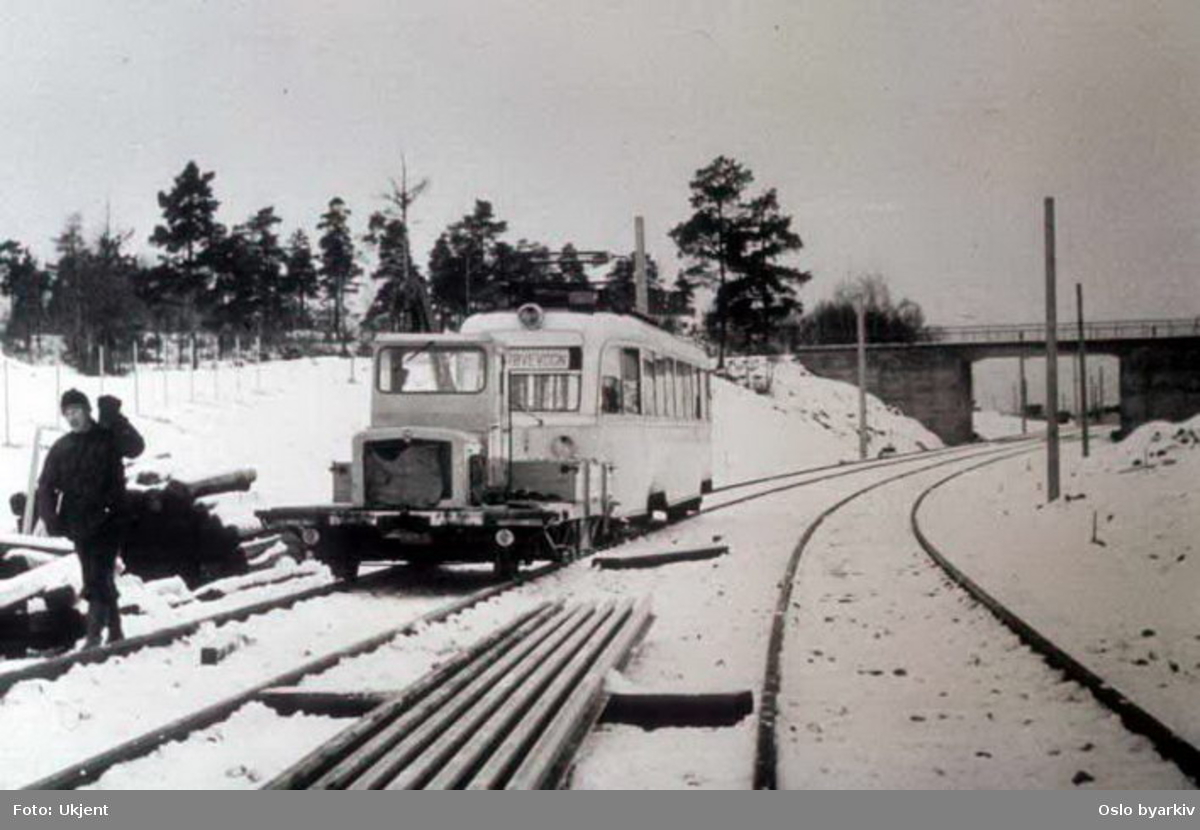 Oslo Sporveier. Trikk motorvogn 158 type Gullfisk B2 på vinterføre trekkes av Robeltralle ved Munkelia på Lambertseterbanen. Strekningen Høyenhall-Bergkrystallen satt i drift i 1957 med bytrikker fra linje 4, Kjelsåsbanen. (T-banedrift fra 1966.)