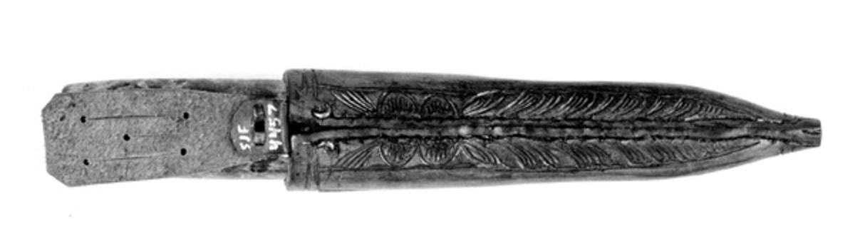 Tolleknv i slire. Knivbladet er smidd av Svein Svimbil (1888-1987) fra Tinn mens det er Emil Flåstøyl (1896-1984) som har vært mester for skaft og slire. Flaten skal ha ferdigstilt denne kniven i 1979.

Kniven er 19,6 centimeter lang, målt fra bladspissen til den bakre enden av skaftet. Bladdelen er 9,3 centimeter lang. Bredden, målt ved brystningen, er 1,9 centimeter. Her er det imidlertid en profilert forhøyning, en «krull» eller «smellopp» på bladryggen. Framfor denne er bladbredden cirka 1,5 centimeter. Tjukkelsen på bladet, målt innerst på bladet, er 4,3 millimeter. Den bakre delen av bladryggen er rettlinjet, mens den fremre delen buer en aning nedover mot bladspissen. Smeden har stemplet inn initialer og adresse - «S.T.TINN» - bakerst på det som når kniven holdes i arbeidsstilling er den venstre sidseflata. T-en i «S.T.» står for Tverberg, som var etternavnet smeden brukte før han flyttet til bruket Svimbil. Skaftet lagd av flammet bjørkevirke. Det er rett, konvekst i lengderetningen og ovalt i tverrsnitt. Største tverrsnitt er 2,1 X 3,0 centimeter. Skaftet er brunbeiset og innsatt med blank klarlakk. 

Slira er sydd av om lag 3,6 millimeter tjukt brunfarget lær. Den er rett og symmetrisk om midtaksen i lengderetningen. Sliresømmen er plassert på den sida som vil vende inn mot kroppen når knivstellet bæres i beltet. Lengden er 16,7 centimeter. Opphenget er ikke inkludert i dette lengdemålet. Yttermålet ved sliremunningen er 3,6 centimeter. Slira har ingen metallbeslag. Den er imidlertid prydet med utskåren dekor. På forsida er det snakk om akantusranker. På baksida er det bladfliker som tilsynelatende har «vokst» ut med sliresømmen som stengel. Opprinnelig presset Flåstøyl inn motiv i det våte læret med syl eller liknende. Den ferdig dekorerte slira lakkeres først med kvistlakk. Så pusser han den av på overflata og lakkerer over med en blank lakk. På innsida av sliremunningen er det innstukket ei ståltrådhempe som opphenget - en lysebrun lærestrimmel med tre innskårne spalter for feste i et smalt belte eller en knapp i bukselinninga til knivbrukeren.