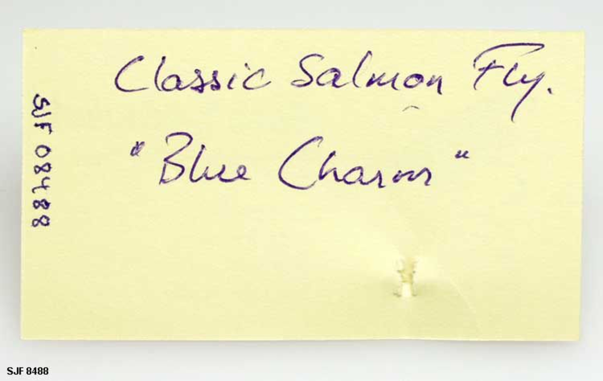 Lakseflue bundet etter mønster fra George M. Kelson's bok The Salmon Fly. How to dress it -How to use it. 1895. Flua er en Classic Salmon Fly med navnet "Blue Charm". 