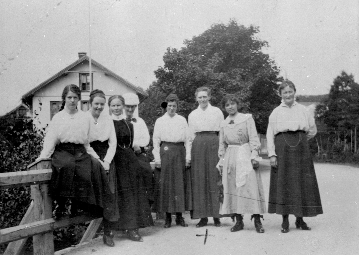 8 damer på brua ved Byflaten, Veldre, Ringsaker. Samvirkelaget bak.