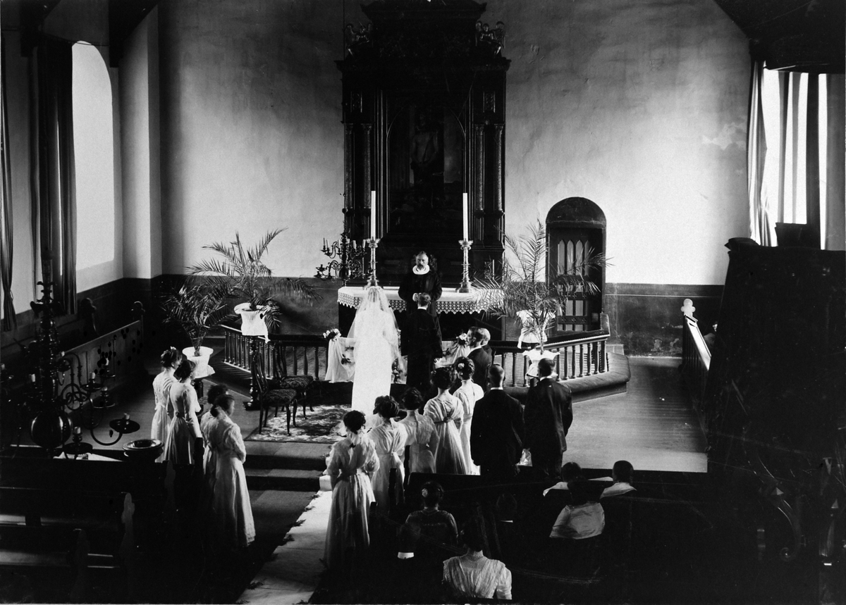 Bryllup i Furnes kirke, Ringsaker ca. 1905-1910. Brudepar foran alteret med prest, forlovere og ni brudepiker.
